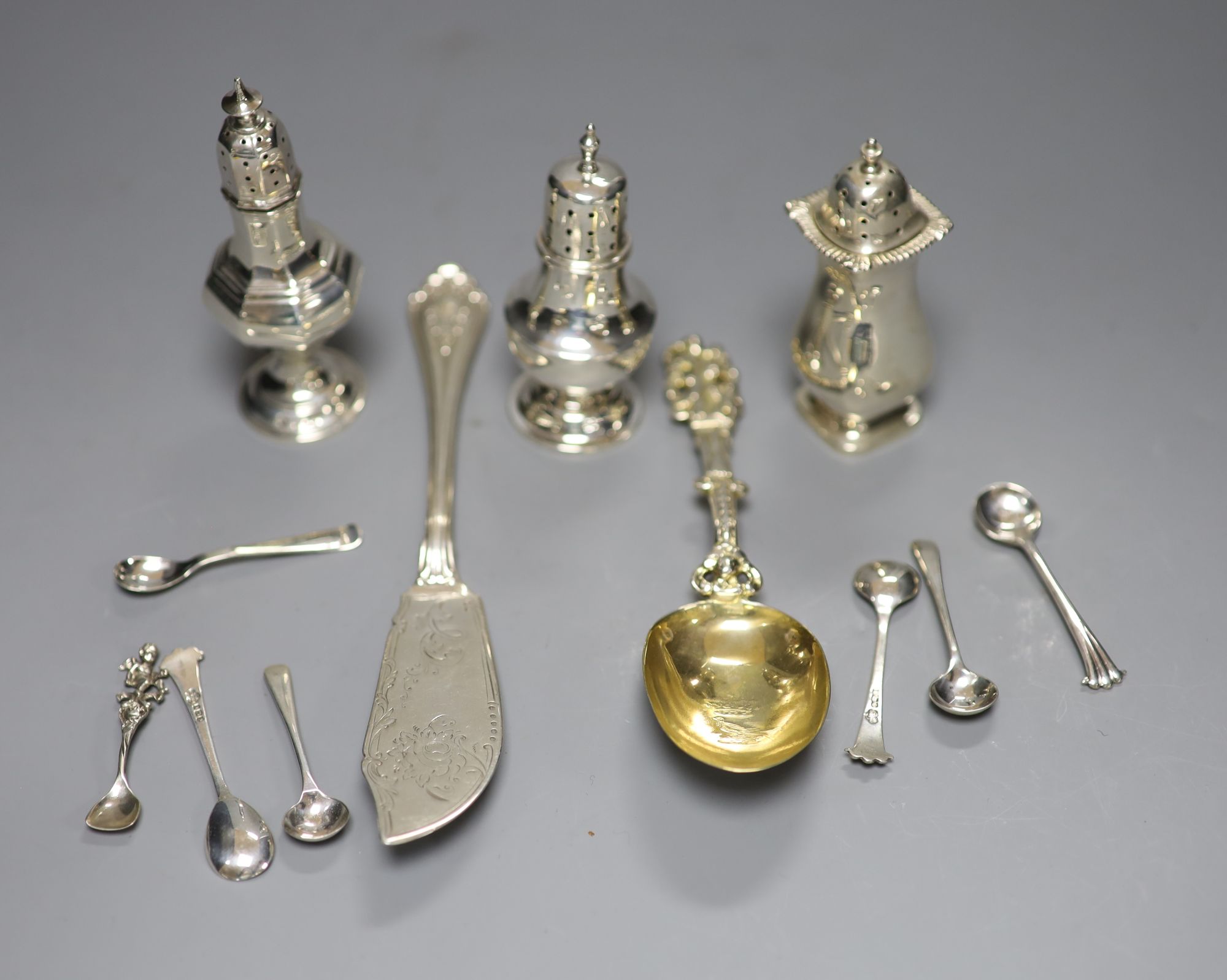 A Victorian silver butter knife, an ornate Dutch white metal spoon, seven condiment spoons including six silver, one 835 & 3 peppers.
